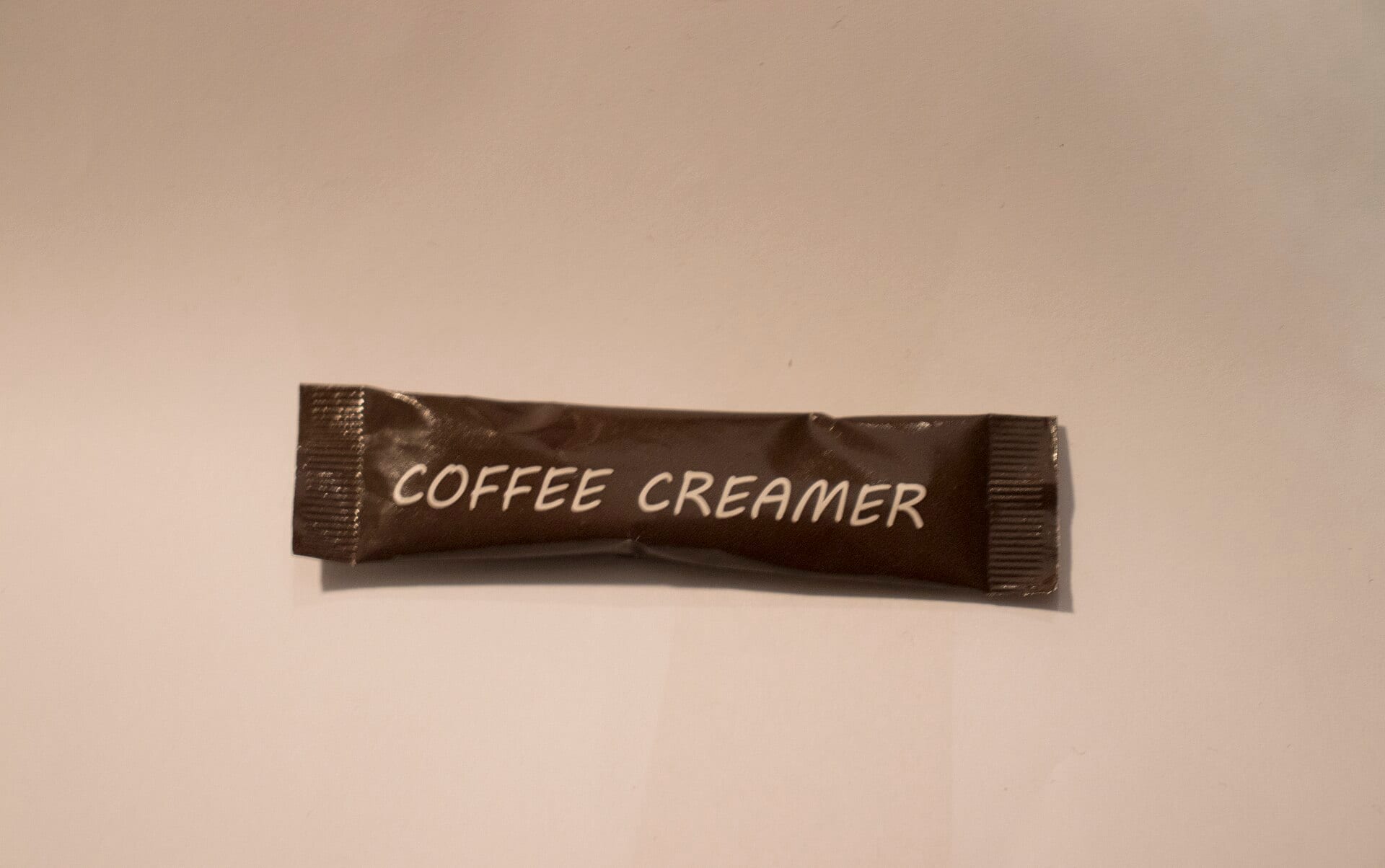 A single-serve stick of coffee creamer on a plain surface