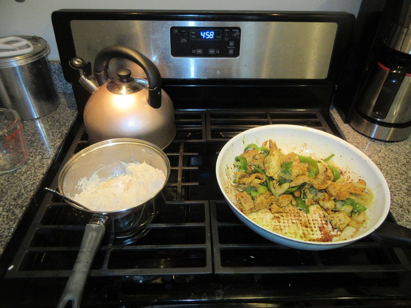 A home-cooked dinner on a stove, with rice in a pan and a stir-fry in a skillet