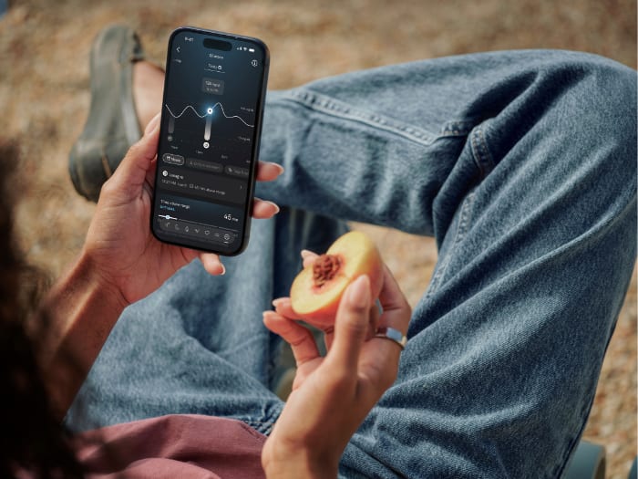 A person holding a phone showing the Oura app while wearing an Oura ring