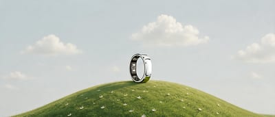 A silver RingConn smart ring standing on a grassy hill under a pale sky