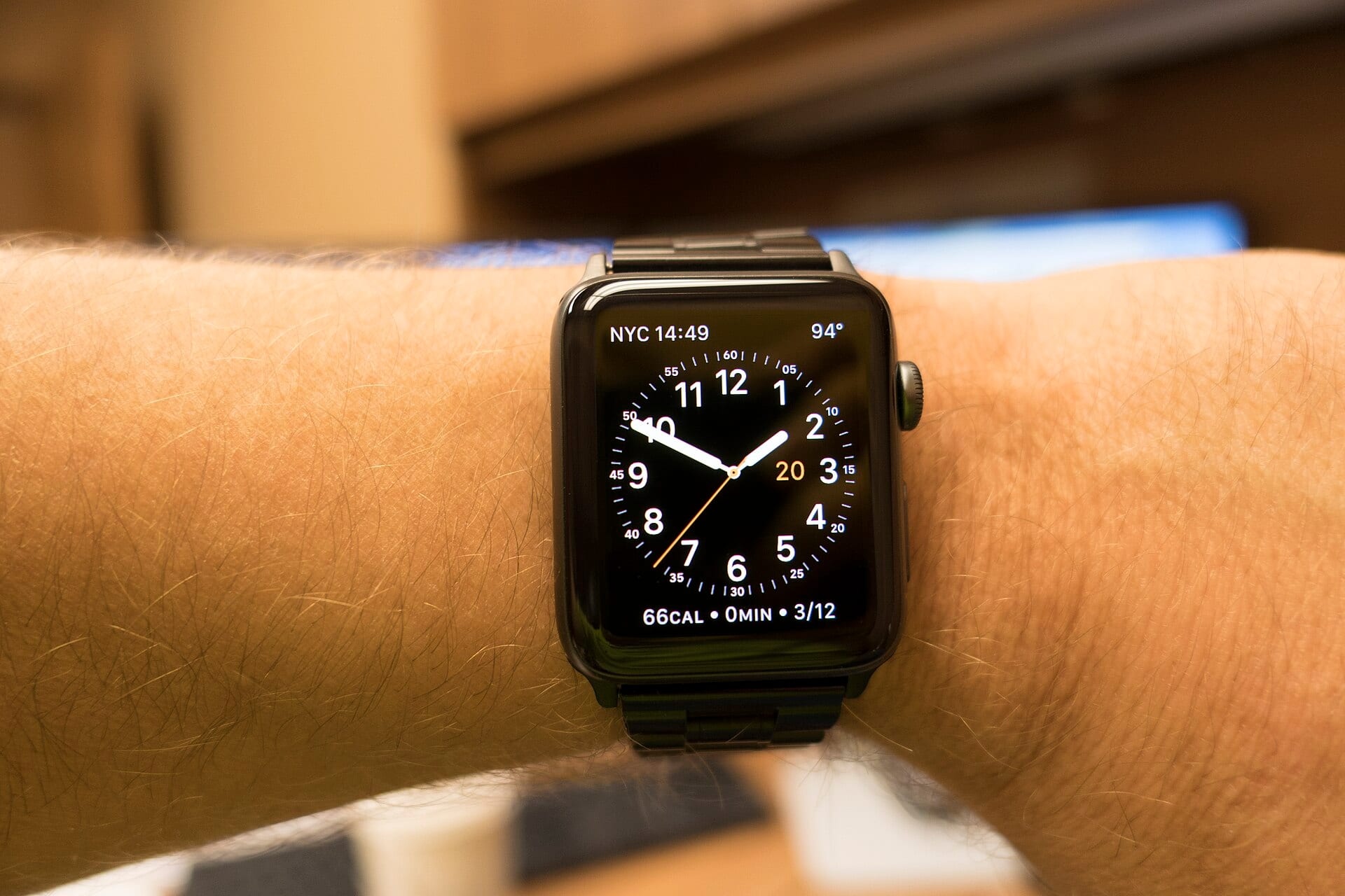 A smartwatch with a black link band on a wrist