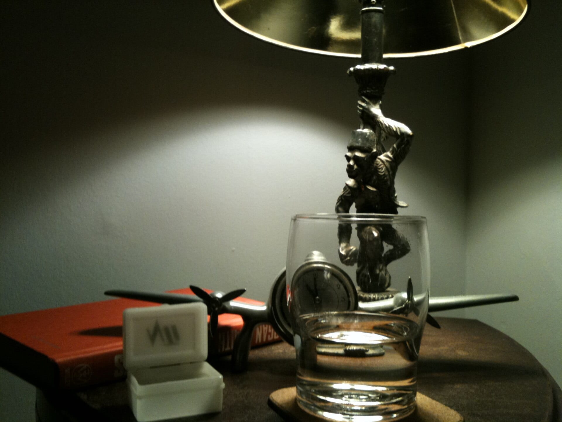 A bedside table with a lamp, a glass and a book